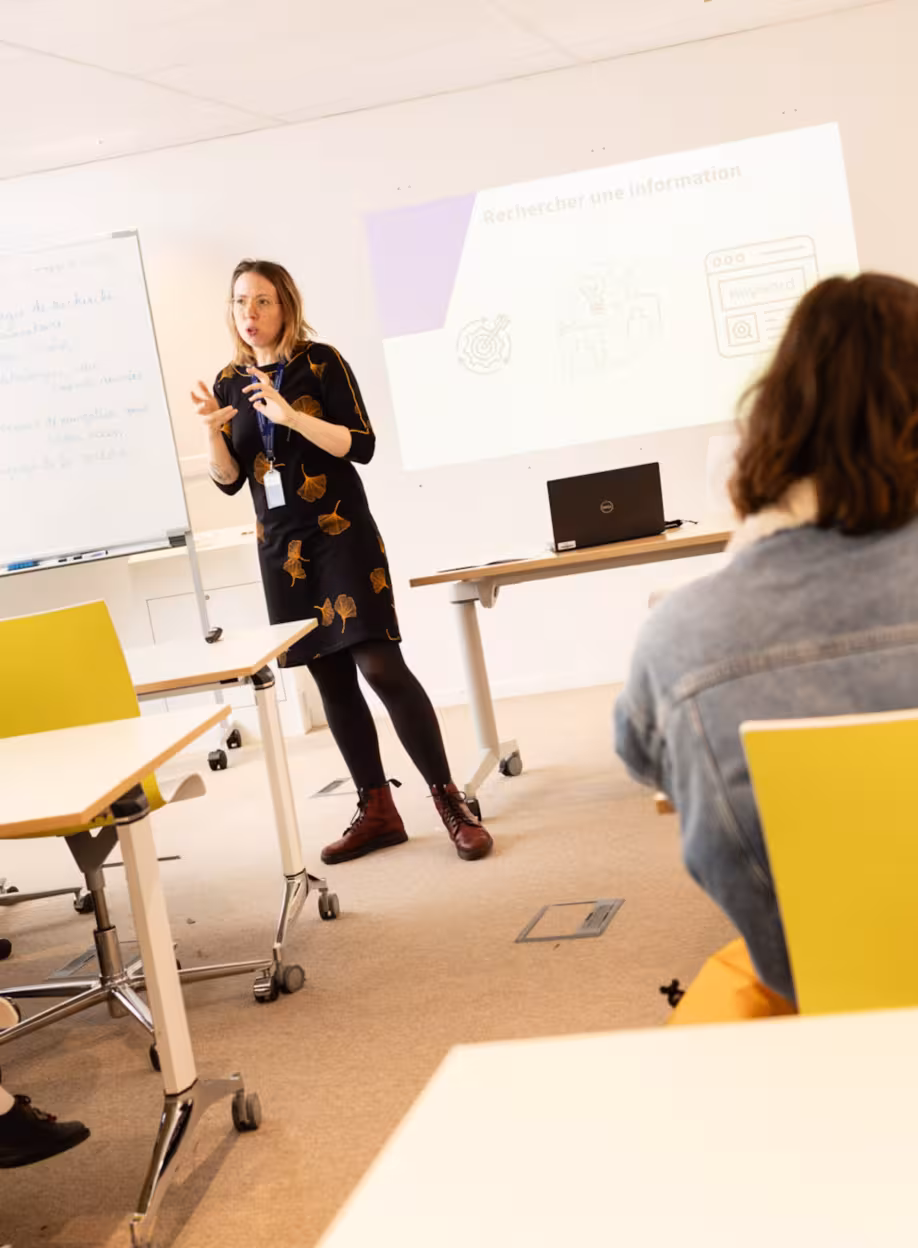Une enseignante donne un cours à des étudiants dans une salle de classe universitaire.